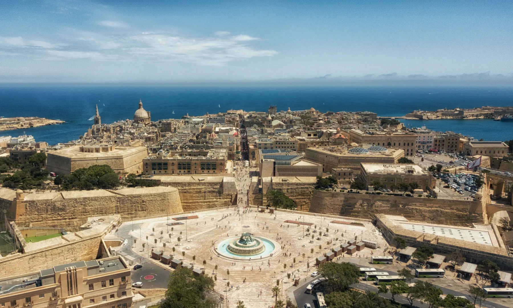 Aerial view of Valletta: the city gate plaza and fountain, bastion walls and the harbour beyond